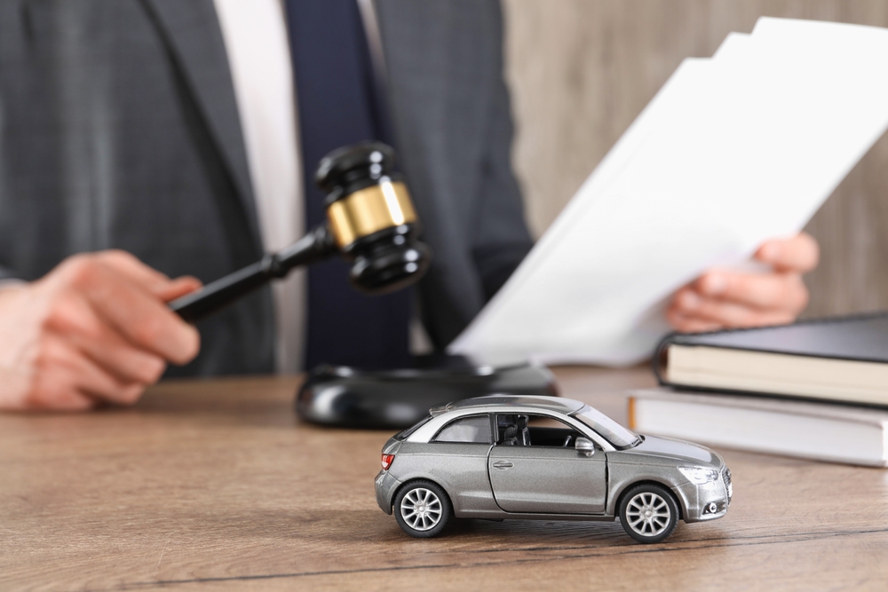 What to Do After a Car Accident in Seattle - Khan Injury Law Auto accident law. Man with document and gavel at wooden table indoors, focus on toy car